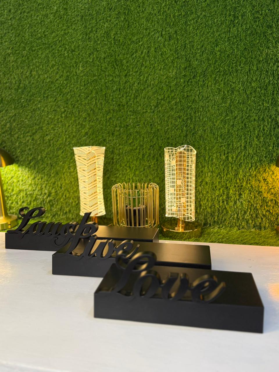 Decorative items including a black box with 'Lunch' and 'Dinner' signs, a gold candle holder, and a gold decorative piece on a green grass-like background.