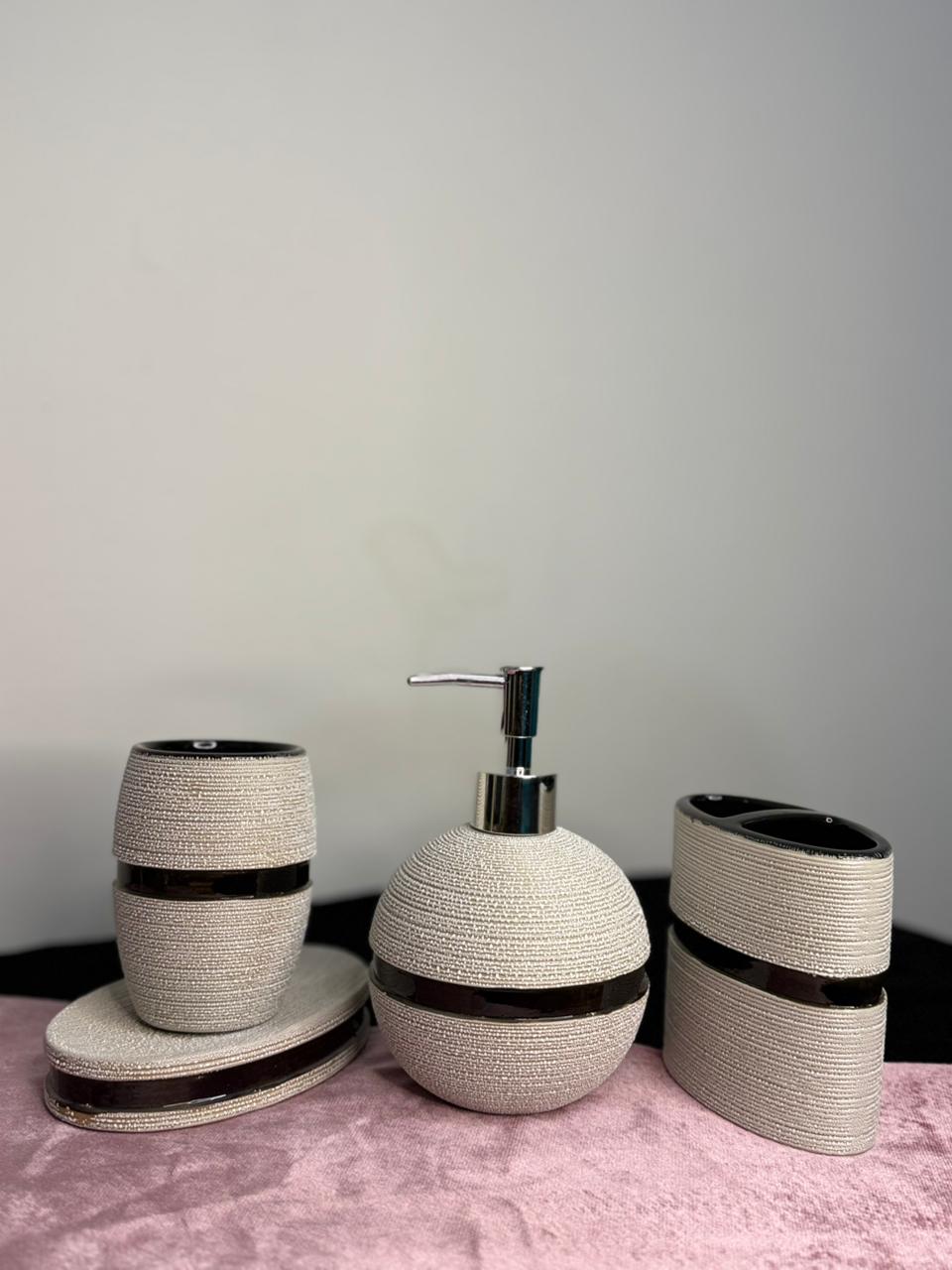 Bathroom accessory set with a soap dispenser, toothbrush holder, and container on a pink surface.