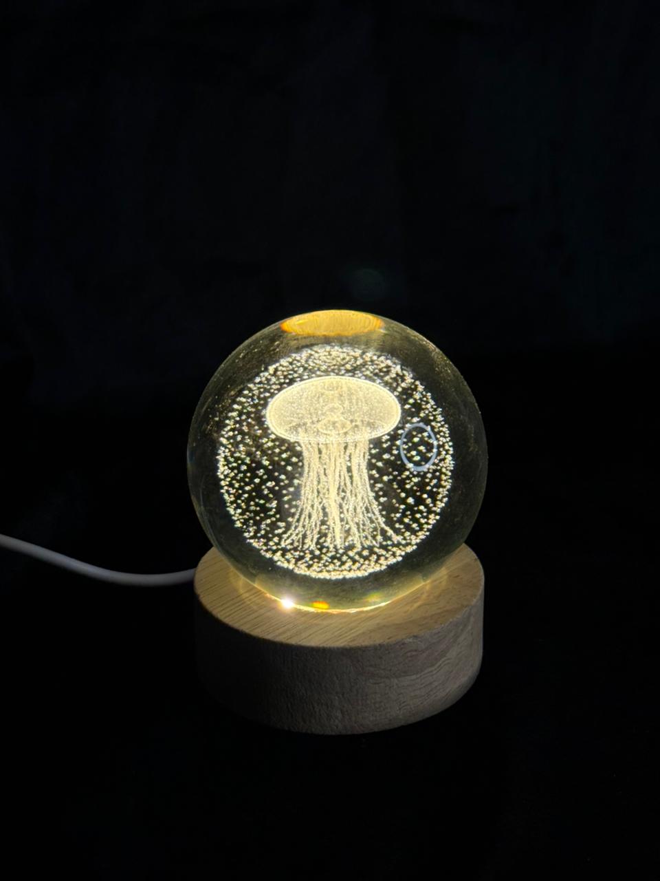 Decorative lamp with jellyfish design inside a crystal ball on a wooden base against a black background